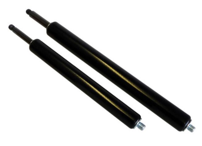 Zdjęcie przedstawiające parę siłownik&oacute;w gazowych zainstalowanych w praktycznym zastosowaniu, np. przy dużej, ciężkiej klapie, bramie maszynowej lub pokrywie serwisowej. Siłowniki są zamocowane pod kątem, wyraźnie wspomagając podnoszenie i utrzymywanie klapy w pozycji otwartej. Otoczenie to hala produkcyjna lub przemysłowa maszyna (dominują szarości i metaliczne powierzchnie). Ujęcie demonstruje funkcjonalność sprężyn gazowych: ułatwianie obsługi, spowalnianie ruchu i bezpieczne utrzymywanie ciężaru.