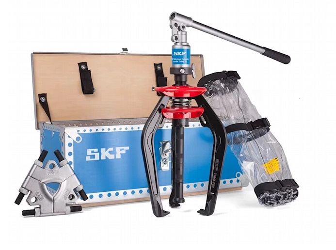 Kompletny Zestaw do Demontażu SKF TMMA 75H SET w DAKAM Obraz jest ucieleśnieniem wszechstronności i profesjonalnego przygotowania do każdego zadania serwisowego. Prezentuje nie tylko samo narzędzie, ale kompletny system (SET) zamknięty w jednej walizce, rozwiązujący problem demontażu łożysk nawet w trudno dostępnych miejscach. Kompozycja łączy techniczną elegancję uporządkowanego zestawu z logistyczną sprawnością autoryzowanego polskiego dystrybutora DAKAM. Dominują barwy: czarny mat (ściągacz), stal (płyty) oraz biel/błękit opakowań SKF. Mobilny warsztat w jednej walizce: W centrum uwagi, na czystym stole warsztatowym, znajduje się otwarta, solidna metalowa walizka z idealnie dopasowanymi wkładkami, prezentująca zawartość zestawu SKF TMMA 75H SET: &bull;	Ściągacz Hydrauliczny (TMMA 75H): Centralny element &ndash; znany z poprzednich ujęć ściągacz z zintegrowaną pompą i siłownikiem (75 kN). Jego obecność w zestawie gwarantuje siłę. &bull;	Płyta do Odklejania (Tri-section Pulling Plate): Kluczowy wyr&oacute;żnik wersji "SET". Widoczna jest tr&oacute;jdzielna płyta (model TMMS 100), umieszczona w dedykowanym gnieździe lub zaprezentowana obok ściągacza. Jej ostre krawędzie wizualnie komunikują możliwość uchwycenia łożyska za pierścień wewnętrzny, tam gdzie zwykłe ramiona nie mają dostępu. To rozwiązanie problemu łożysk osadzonych "na płasko". &bull;	Przedłużki Ramion: Widoczne są stalowe przedłużki, kt&oacute;re pozwalają zwiększyć zasięg narzędzia. &bull;	Koc Ochronny: Zwinięty w przegrodzie koc/siatka ochronna, podkreślający dbałość o BHP. &bull;	Porządek i Gotowość: Całość wygląda na idealnie zorganizowaną &ndash; każde narzędzie ma swoje miejsce, co sugeruje profesjonalizm serwisanta i brak ryzyka zgubienia element&oacute;w. Sprawdzony Polski Dystrybutor DAKAM: Tło jest subtelnie rozmyte (efekt bokeh), ale buduje zaufanie: &bull;	Magazyn DAKAM: W tle widać stos zamkniętych walizek SKF SET, gotowych do wysyłki. Potwierdza to, że DAKAM posiada te zaawansowane zestawy na stanie magazynowym. &bull;	Logo Dystrybutora: W dyskretnym, ale widocznym miejscu umieszczone jest logo DAKAM, z dopiskiem "Autoryzowany Dystrybutor Narzędzi SKF". Obraz niesie jasny komunikat: "W DAKAM kupisz nie tylko ściągacz, ale kompletne rozwiązanie. Zestaw SKF TMMA 75H SET zawiera hydrauliczny ściągacz EasyPull oraz tr&oacute;jdzielną płytę do odklejania, co pozwala na bezpieczny demontaż każdego łożyska, nawet tego przylegającego do oprawy".